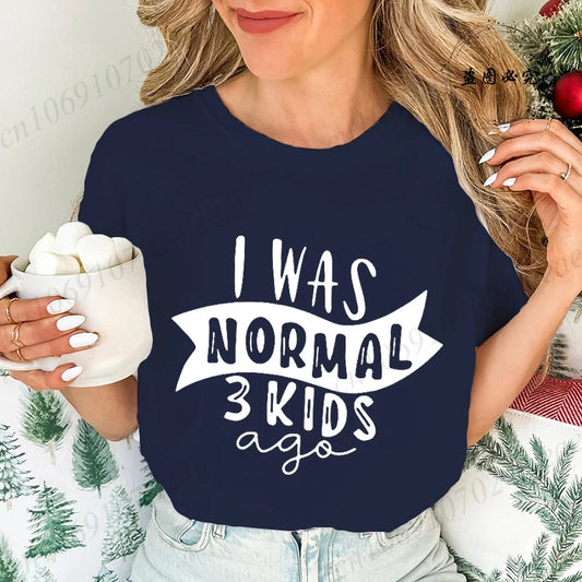 Funny mom t-shirt with the phrase 'I was normal 3 kids ago' worn by a smiling woman holding a mug.